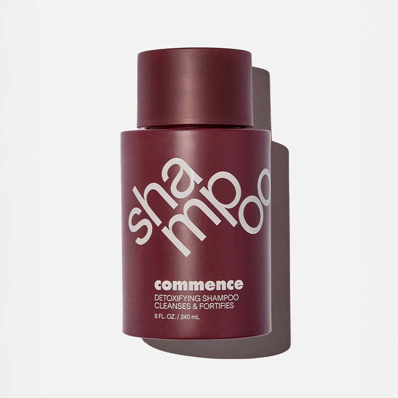 A bottle of detoxifying shampoo with a dark red cap and maroon label with the word 'shampoo' written in large white letters.